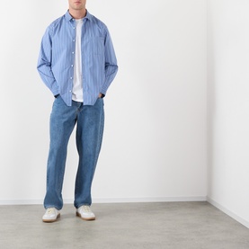 Model wearing A.P.C. blue grey cotton casual shirt with white tee, styled with mid-wash jeans and white trainers.