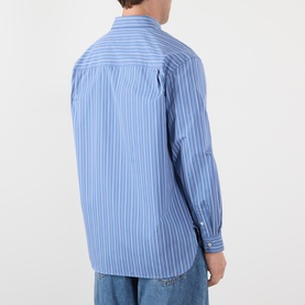 Model wearing A.P.C. blue grey striped cotton casual shirt, rear view showing long sleeves and relaxed fit.