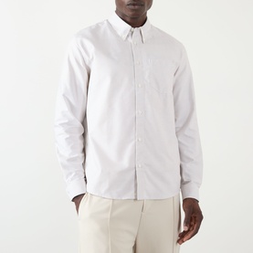 Model wearing A.P.C. beige cotton casual shirt with button-down collar and chest pocket, styled with cream trousers