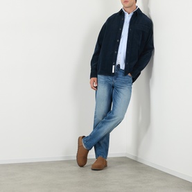 Model wearing A.P.C. Martin Straight-Leg Jeans in washed indigo, styled with a navy jacket, blue shirt and tan suede shoes.