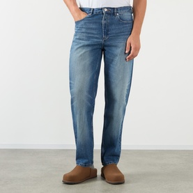 Model wearing A.P.C. Martin Straight-Leg Jeans in washed indigo, mid-rise straight-leg fit with five-pocket styling, styled with tan suede slippers