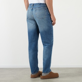 Model wearing A.P.C. Martin Straight-Leg Jeans in washed indigo, rear view, styled with tan suede moccasins.