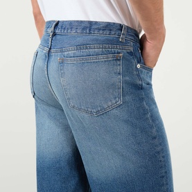 Model wearing A.P.C. Martin Straight-Leg Jeans in washed indigo, showing rear five-pocket detail and tobacco stitching, styled with a white T-shirt.