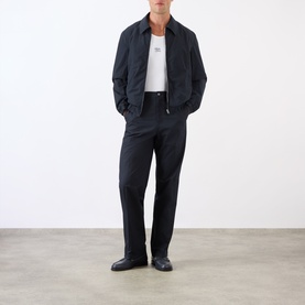 Model wearing A.P.C. dark navy cotton jeans, styled with a matching dark navy jacket and white T-shirt, black loafers