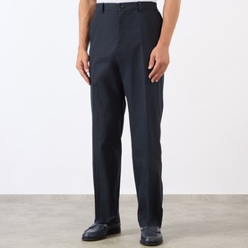 Model wearing A.P.C. dark navy cotton straight-leg trousers with front pleats and belt loops, styled with black loafers