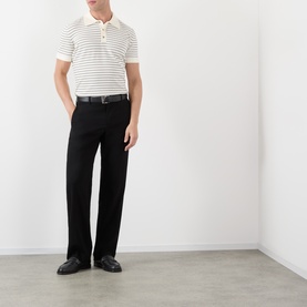 Model wearing A.P.C. natural stripe cotton polo shirt with black trousers and black leather loafers.