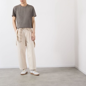 Model wearing cream wide-leg trousers with stripe trim detail, styled with grey t-shirt and white trainers