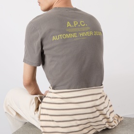 Model wearing A.P.C. grey T-shirt with yellow Automne/Hiver print on back, styled with striped trousers