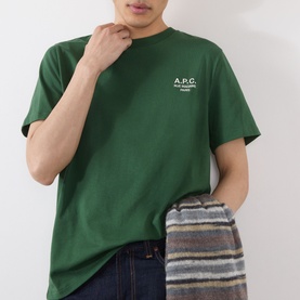 Model wearing A.P.C. dark green cotton T-shirt with small white chest logo print, styled with blue jeans and striped scarf.