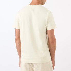 Model wearing A.P.C. Oliver Logo T-Shirt in white, back view, round neck, short sleeves, styled with cream trousers