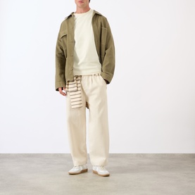 Model wearing A.P.C. Oliver Logo T-Shirt in white, styled with olive jacket and cream wide-leg trousers.