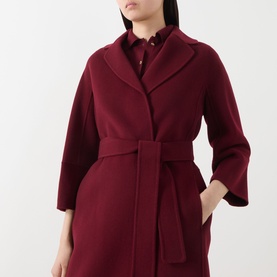 Model wearing Max Mara S bordeaux virgin wool belted coat with wide lapels and three-quarter sleeves, styled over a ruffled collar top.
