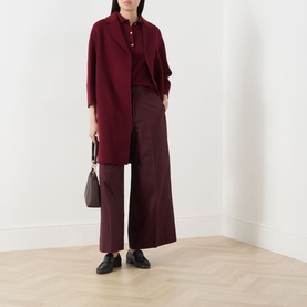 Model wearing Max Mara S bordeaux virgin wool coat, styled with matching shirt and wide-leg trousers, carrying a small dark bag.