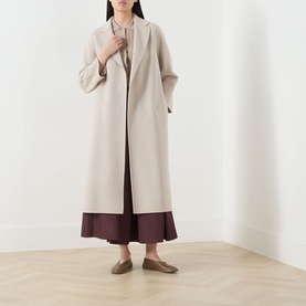 Model wearing Max Mara S Esturia Belted Wrap Coat in beige, longline with notched lapels, styled with burgundy wide-leg trousers and taupe flats.