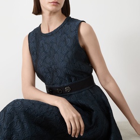 Model wearing Max Mara S Midnight Blue sleeveless jacquard dress with swirl texture, styled with a dark belt featuring ornate buckle detail.