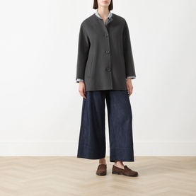 Model wearing Max Mara S Jour Wide-Leg Joggers in Midnight Blue denim, styled with a grey collarless coat and brown loafers.