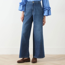 Model wearing Max Mara S China Blue wide-leg jeans, styled with a blue ruffled top and brown loafers.