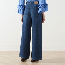 Model wearing Max Mara S China Blue wide-leg jeans, rear view, styled with a blue ruffled bell-sleeve top.