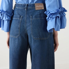 Model wearing Max Mara S China Blue wide-leg jeans, back view showing patch pockets and branded label, styled with a blue ruffled blouse.