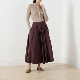 Model wearing Max Mara S Limone Beige Knitted Polo Shirt, styled with a dark burgundy midi skirt and tan loafers.