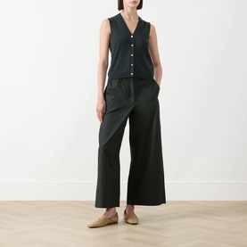 Model wearing Max Mara S Saggio Knitted Vest in green, V-neckline, front button fastening, styled with wide-leg dark trousers and tan mules.