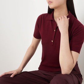 Model wearing Max Mara S red cotton silk cashmere knit polo top with short sleeves and gold buttons, styled with burgundy trousers
