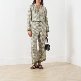 Model wearing Max Mara S Dice Silk Pyjama Shirt in Kaki Dice with matching wide-leg trousers, styled with black sandals and mini bag.