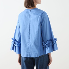 Model wearing Max Mara S light blue cotton shirt, back view, with ruffled flared cuffs, styled with blue jeans.