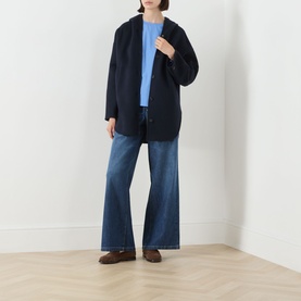 Model wearing Max Mara S light blue cotton shirt, styled with navy oversized coat, wide-leg denim jeans and brown loafers.