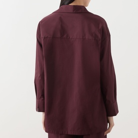 Model wearing burgundy oversized long-sleeve shirt, rear view, relaxed fit with dropped shoulders and curved hem