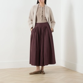Model wearing Max Mara S Romina Flared Skirt in red, midi length with side pockets, styled with a beige cardigan and flat shoes.