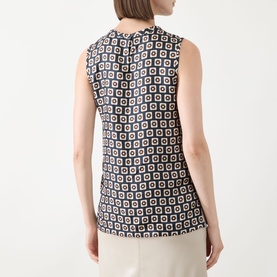 Model wearing Max Mara S Giornata Silk Printed Blouse in ultramarine geometric print, sleeveless with crew neck, rear view, styled with cream trousers