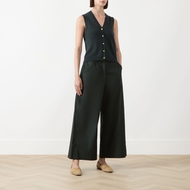 Model wearing Max Mara S green wide-leg cotton trousers, styled with a dark sleeveless knit top and nude flat shoes.
