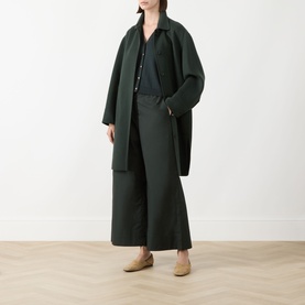 Model wearing Max Mara S green wide-leg cotton trousers, styled with a matching green coat, dark shirt, and beige flat shoes.