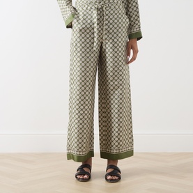 Model wearing Max Mara S Kaki Dice silk trousers with geometric print, styled with matching top and dark sandals.