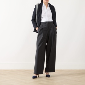 Model wearing Max Mara S Taro High-Waisted Wide Leg Trousers in dark grey wool, styled with a white shirt, black blazer and navy heels.