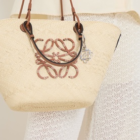 Loewe Anagram Logo Keyring in palladium brass, shown attached to a raffia tote bag with tan leather handles.