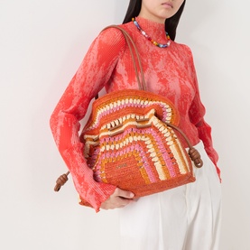 Model carrying Loewe Flamenco Crochet Medium Clutch in bright orange and pink raffia with ruffled top, styled with red lace top and beaded necklace