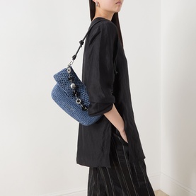 Model carrying Loewe Ola Denim Crochet Medium Shoulder Bag in denim blue with silver donut chain detail, styled with black oversized jacket and