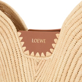 Loewe raffia shoulder bag in natural and tan, showing interior tan calfskin lining with embossed Loewe logo and scalloped edge detail.