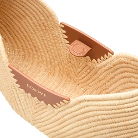 Loewe raffia shoulder bag in natural and tan, close-up of woven raffia body with tan calfskin leather trim and branded detail