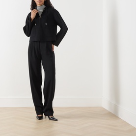 Model wearing Max Mara Studio black virgin wool, silk and cashmere short coat, styled with matching black trousers and black heels.