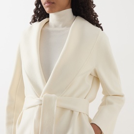Model wearing Max Mara Studio white wool-silk-cashmere belted coat with shawl collar, styled with a white turtleneck.