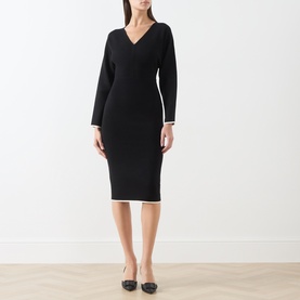 Model wearing Max Mara Studio black and white knit midi dress with V-neck, long sleeves, and contrast white trim detailing.