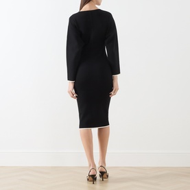 Model wearing Max Mara Studio black and white long-sleeve fitted knit dress, shown from behind, styled with brown heeled mules.