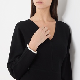 Model wearing Max Mara Studio black and white dress with V-neckline and white cuff detail, styled with a delicate ring.