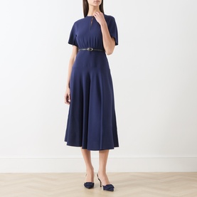 Model wearing Max Mara Studio navy dress with short sleeves, flared midi skirt and slim belt, styled with navy heels.