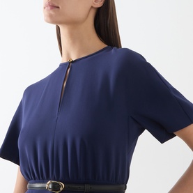Model wearing Max Mara Studio navy dress with gold-tone zip neckline detail and black belted waist, short sleeves.
