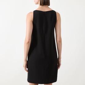 Model wearing a black sleeveless shift dress, rear view showing concealed back zip and clean minimalist silhouette