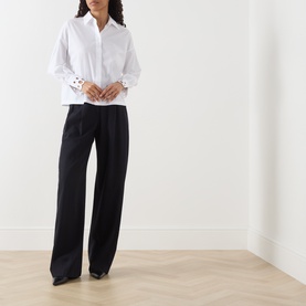 Model wearing Max Mara Studio Staffa Broderie Anglaise Shirt in Optical White with embroidered cuffs, styled with black wide-leg trousers